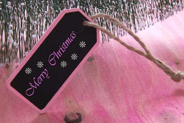 Kerstboom op roze houten achtergrond met label — Stockfoto