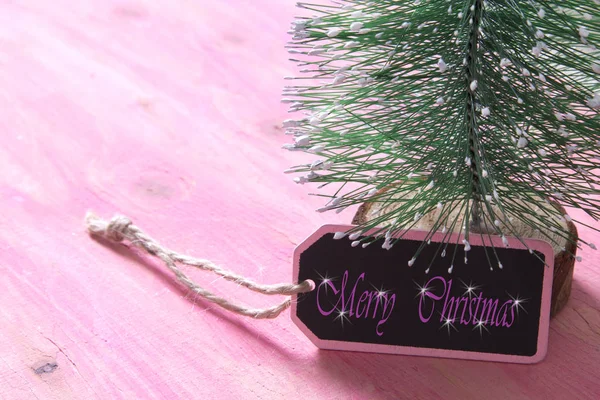 ラベルの付いたピンクの木製の背景上にクリスマス ツリー — ストック写真
