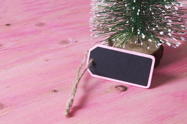 Árbol de Navidad sobre fondo de madera rosa con etiqueta — Foto de Stock