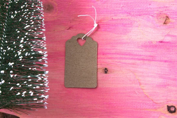 ラベルの付いたピンクの木製の背景上にクリスマス ツリー — ストック写真