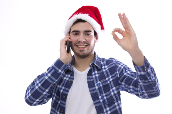 Νεαρός άνδρας με santa μιλώντας στο κινητό τηλέφωνο και επισημαίνοντας καπέλο — Φωτογραφία Αρχείου