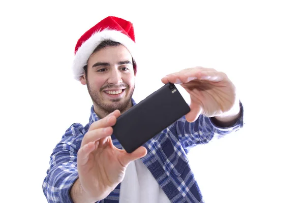 Junger Mann mit Weihnachtsmannhut wird zum Selfie mit dem Handy — Stockfoto