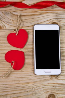 Kalp şeklinde etiketi ve ahşap arka plan üstünde hareket eden telefon