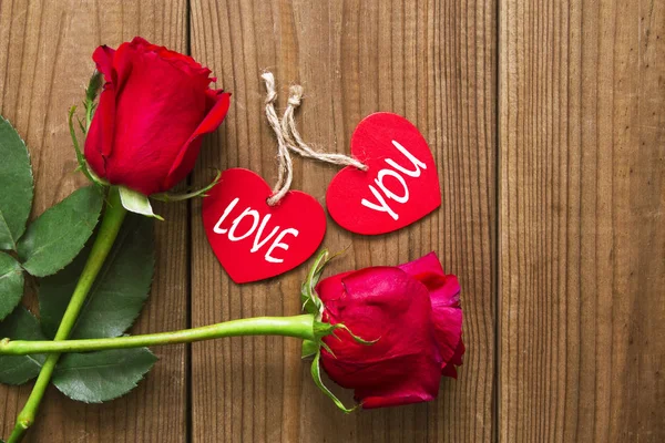 Etikett med romantiska meddelande och röda rosor på trä bakgrund — Stockfoto