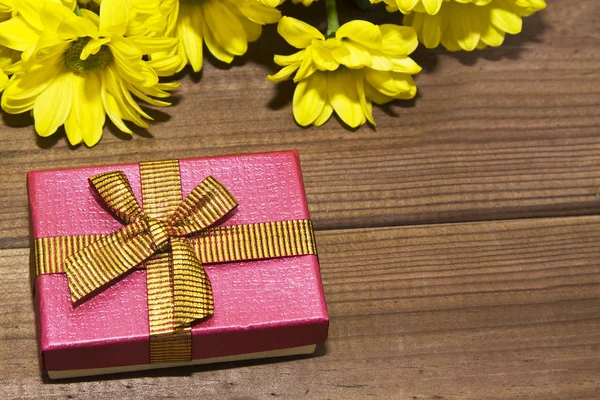 Geschenk box en gele bloemen — Stockfoto