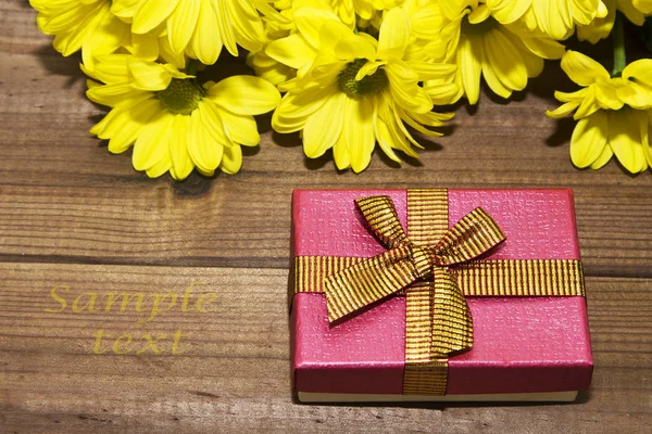 Geschenkbox und gelbe Blumen — Stockfoto