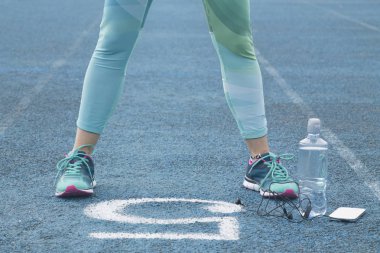 Cep telefonu ile atletik yolda egzersizleri yapıyor kadın