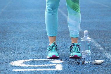 Cep telefonu ile atletik yolda egzersizleri yapıyor kadın