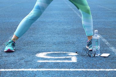 Cep telefonu ile atletik yolda egzersizleri yapıyor kadın