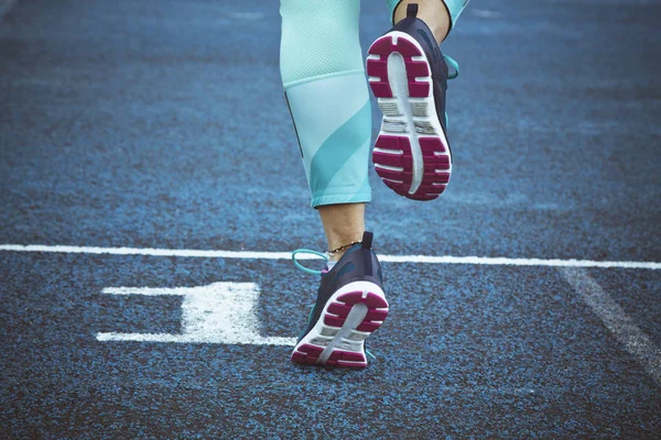 Mujer corriendo en pista azul — Foto de Stock