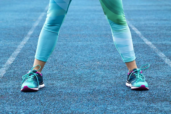 Piernas de mujer en leggins y zapatillas de running en pista de running — Foto de Stock