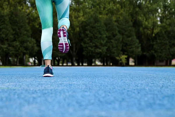 Piernas mujer corriendo sobre azul pista de correr — Foto de Stock