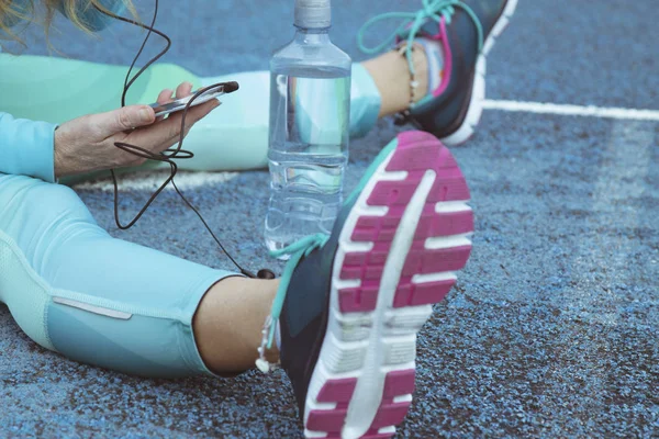 Woman doing sport on track with mobile phone and headset