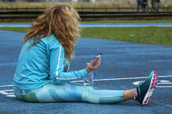 Woman doing sport on track with mobile phone and headset