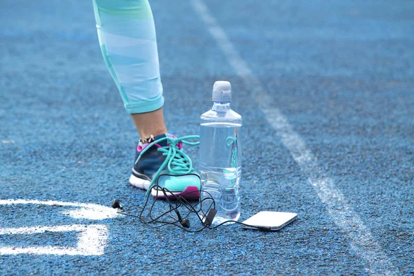 Mujer haciendo ejercicios en pista atlética con teléfono móvil — Foto de Stock