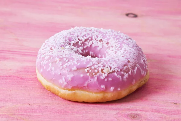 甜甜圈上粉红色的木制背景 — 图库照片