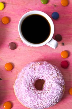 Çörek ve smarties pembe bir arka plan üzerinde kahve