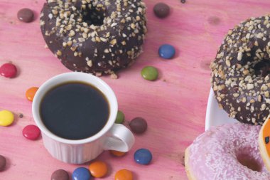 Çörek ve smarties pembe bir arka plan üzerinde kahve