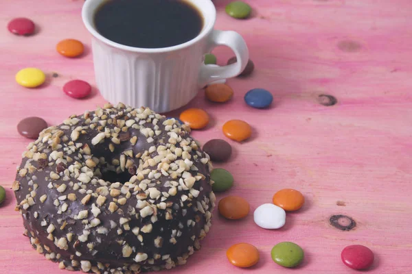 Xícara de café com donuts e smarties em fundo rosa — Fotografia de Stock