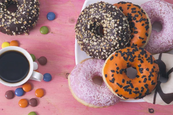 Xícara de café com donuts e smarties em fundo rosa — Fotografia de Stock