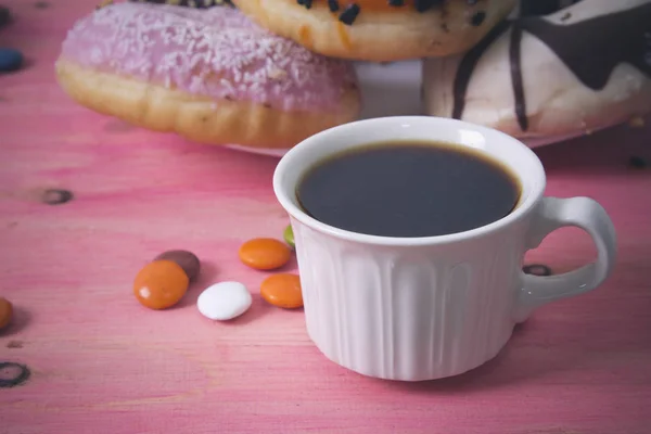 Xícara de café com donuts e smarties em fundo rosa — Fotografia de Stock