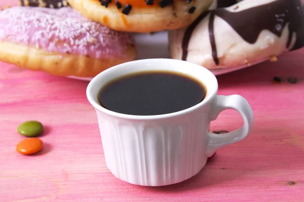 Kopp kaffe med donuts och smarties på rosa bakgrund — Stockfoto