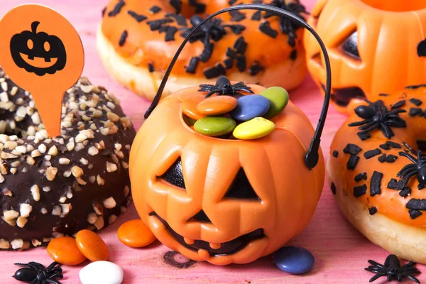 donuts, candy and halloween cakes on pink background