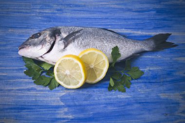 limon ve mavi ahşap bir zemin üzerine maydanoz çipura