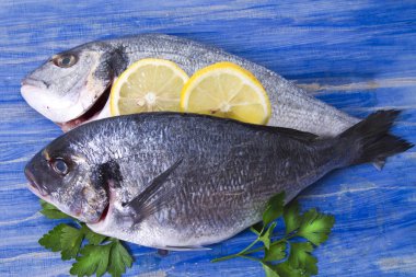 limon ve mavi ahşap bir zemin üzerine maydanoz çipura