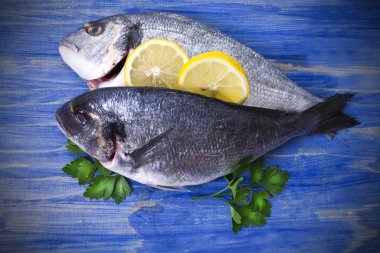 limon ve mavi ahşap bir zemin üzerine maydanoz çipura