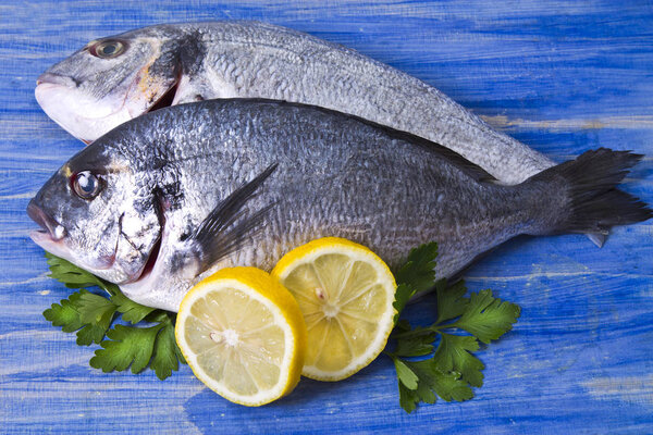 bream with lemon and parsley on a background of blue wood