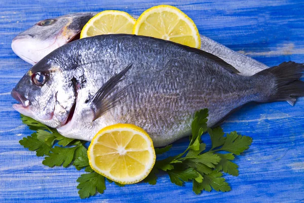 Dorada con limón y perejil sobre un fondo de madera azul —  Fotos de Stock