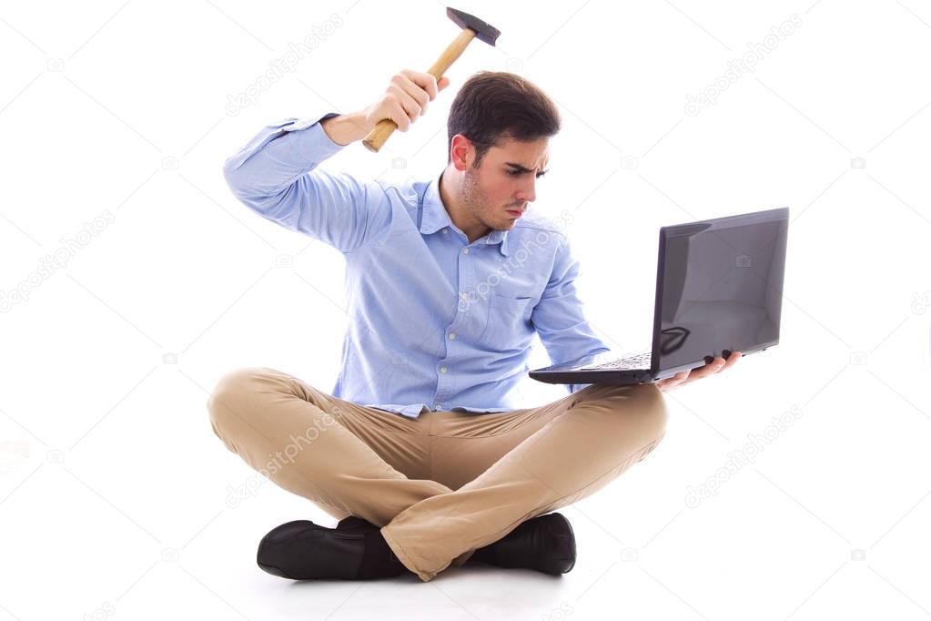 Man sitting on the floor hitting the computer with hammer