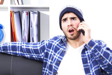 Kızgın genç adam cep telefonu ile Divan