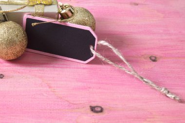 Noel kartı ile etiket, hediye kutusu ve pembe bir arka plan üzerinde Noel topları