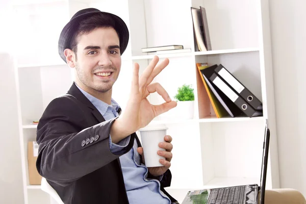 Joven en la oficina con café y símbolo ok — Foto de Stock