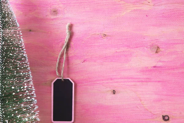 Árbol de Navidad sobre fondo de madera rosa con etiqueta —  Fotos de Stock