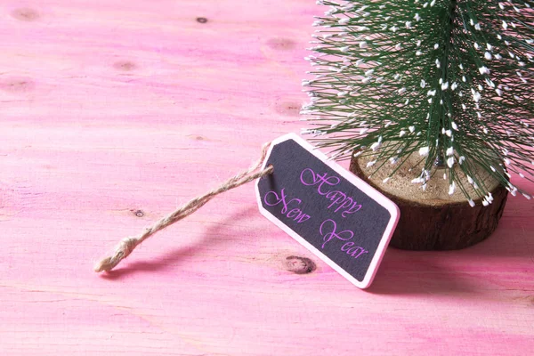 Árbol de Navidad sobre fondo de madera rosa con etiqueta — Foto de Stock