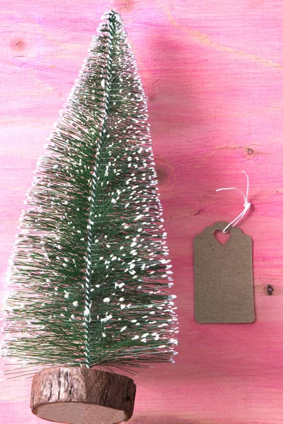 Árbol de Navidad sobre fondo de madera rosa con etiqueta — Foto de Stock