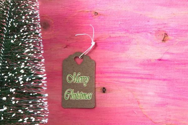 Kerstboom op roze houten achtergrond met label — Stockfoto