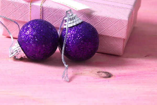 Kerstkaart met label, doos van de gift en kerstballen op roze achtergrond — Stockfoto