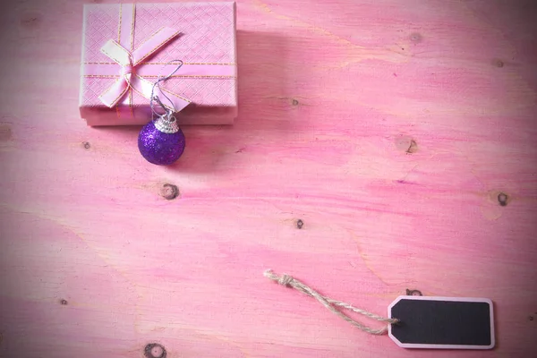 Weihnachtskarte mit Etikett, Geschenkschachtel und Weihnachtskugeln auf rosa Hintergrund — Stockfoto