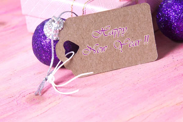 Carte de Noël avec étiquette, boîte cadeau et boules de Noël sur fond rose — Photo