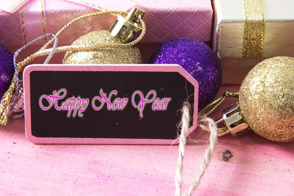 Gelukkig nieuwjaarskaart met luxe-geschenketui en tag op roze houten bakckground — Stockfoto