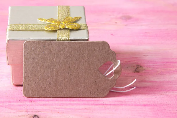 Weihnachtskarte mit Geschenkbox und Anhänger auf rosa Holz — Stockfoto
