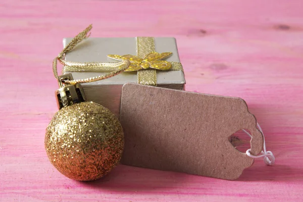 Biglietto natalizio con confezione regalo e cartellino su legno rosa — Foto Stock