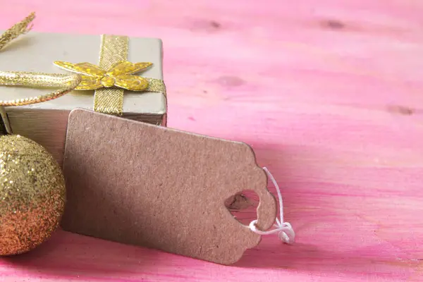 Kerstkaart met luxe-geschenketui en tag op roze houten — Stockfoto