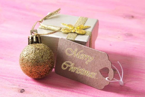 Feliz año nuevo con caja de regalo y etiqueta en bakckground de madera rosa —  Fotos de Stock