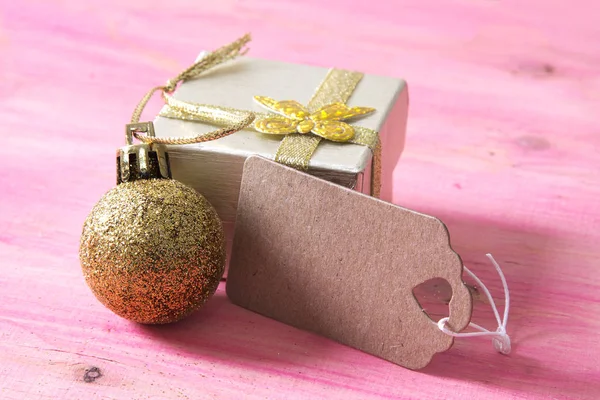 Feliz año nuevo con caja de regalo y etiqueta en bakckground de madera rosa —  Fotos de Stock