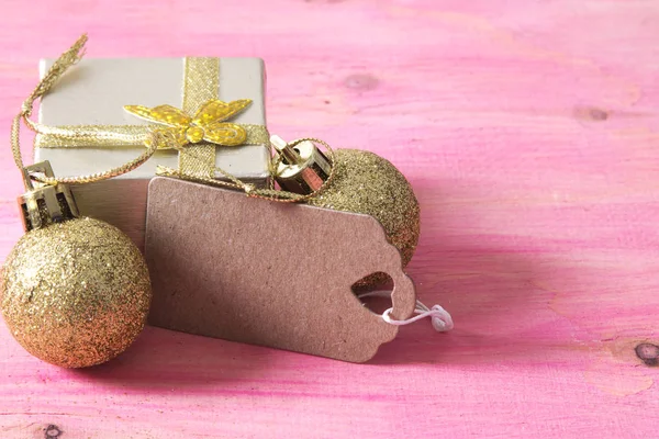 Tarjeta de Navidad con etiqueta, caja de regalo y bolas de Navidad sobre fondo rosa —  Fotos de Stock